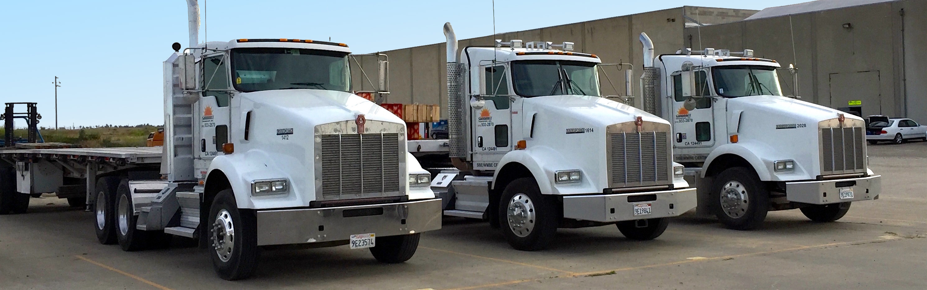 Three flatbed Sundance trucks parked in a row