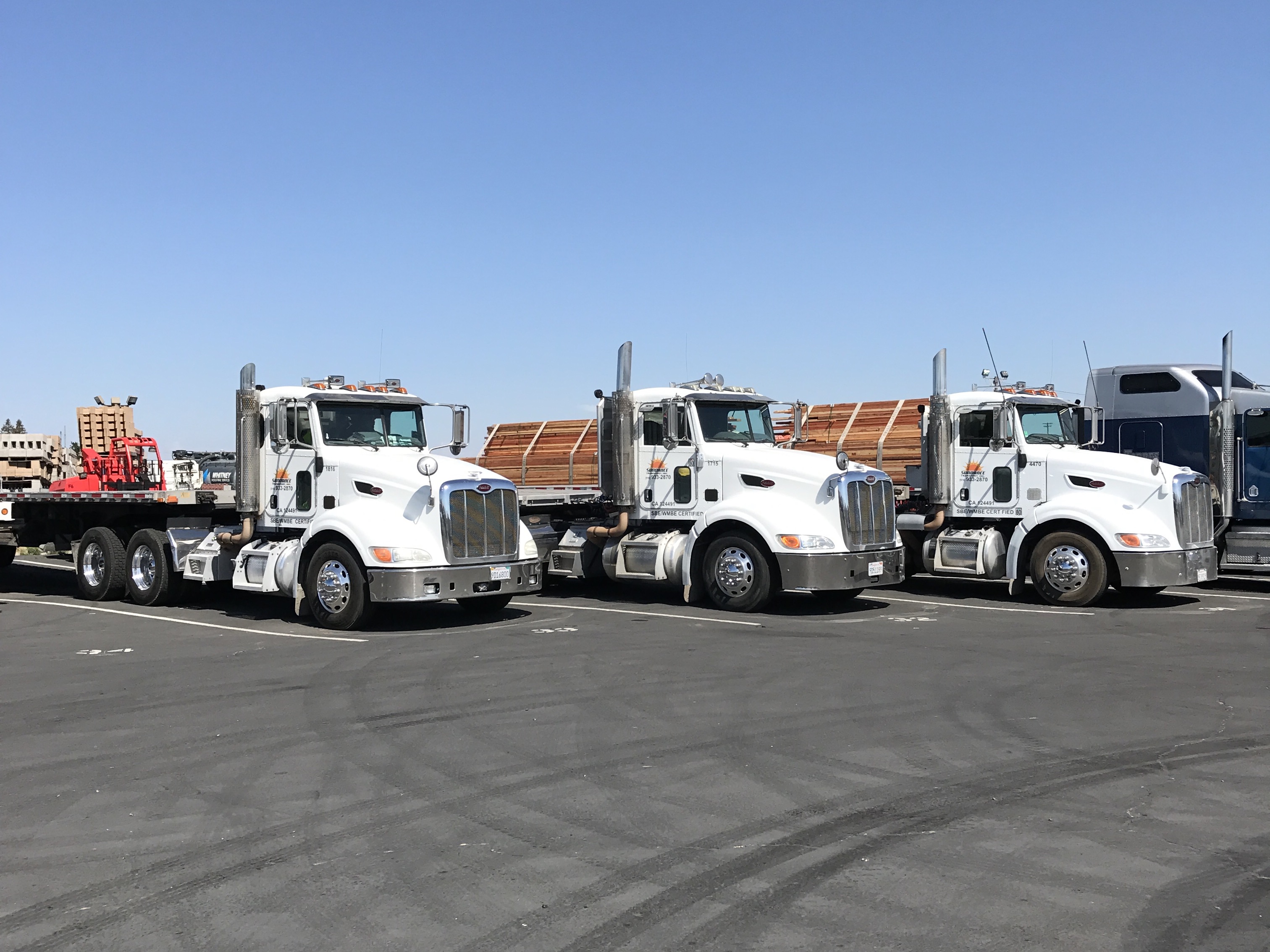 Three flatbed Sundance trucks parked in a yard